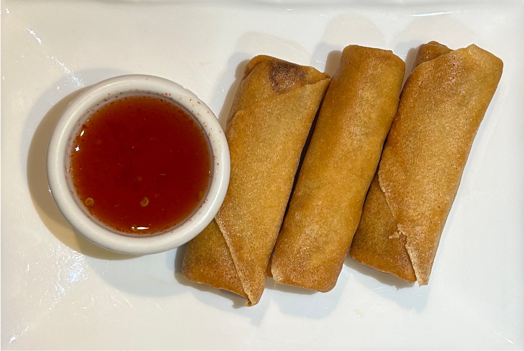 three veggie spring rolls and dipping sauce on a plate